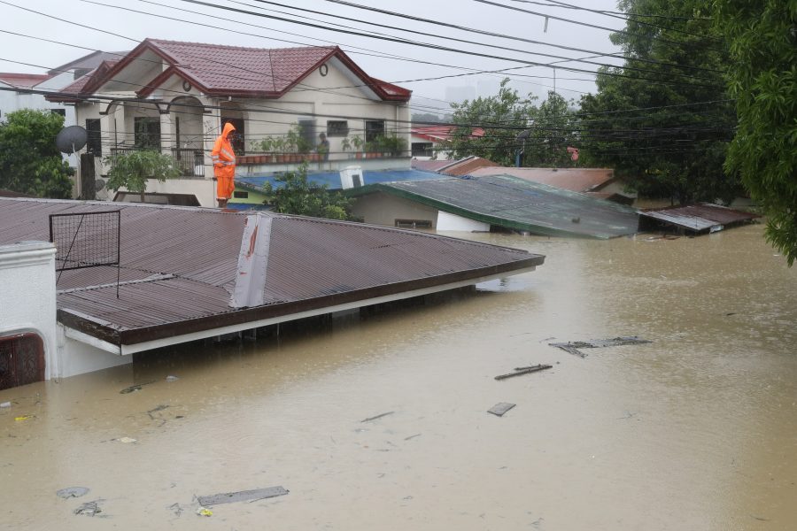 En man står på taket till sitt hem i Marikina i Filippinerna efter att tyfonen Vamco orsakat översvämningar.