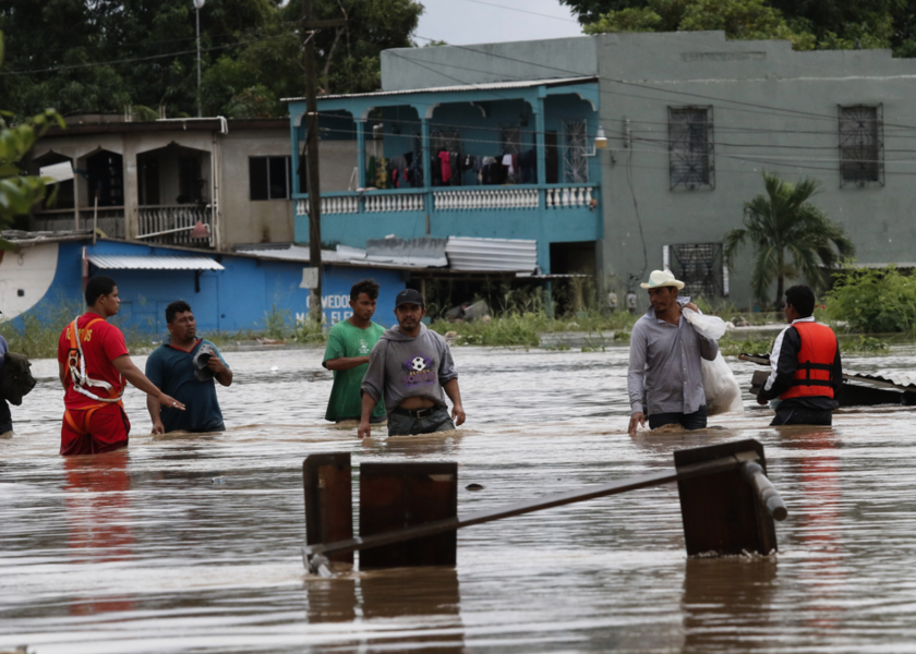 Människor tar sig fram på en översvämmad gata i La Lima, Honduras, efter att orkanen Iota dragit fram.
