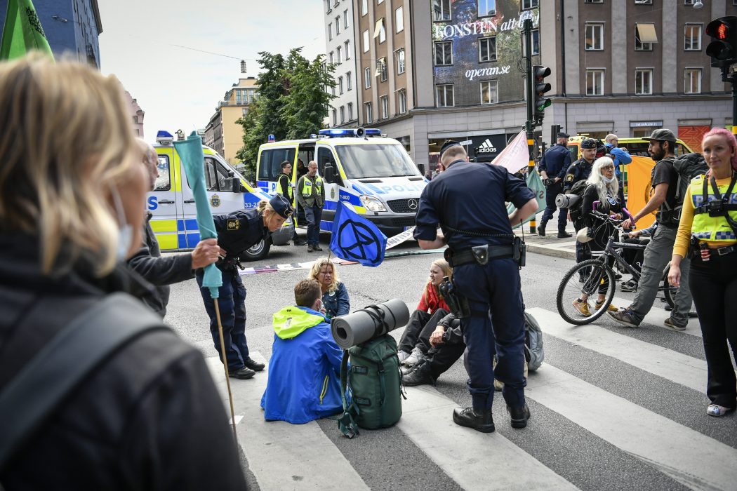 Polis pratar med klimataktivister från miljöorganisationen Extinction Rebellion i samband med en aktion från i somras.