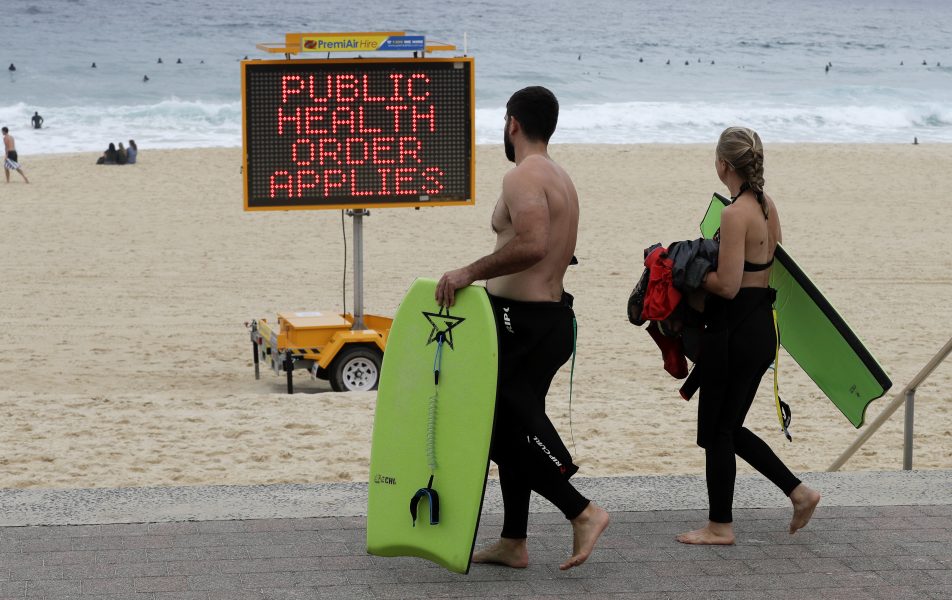 En skylt varnar strandbesökare i Sydney, Australien, för att stranden kan stängas på grund av coronapandemin.