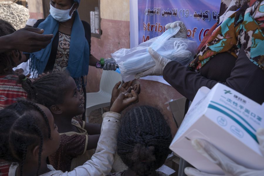 Hjälparbetare delar ut munskydd till barn som flytt från Tigray till ett flyktingläger i östra Sudan.