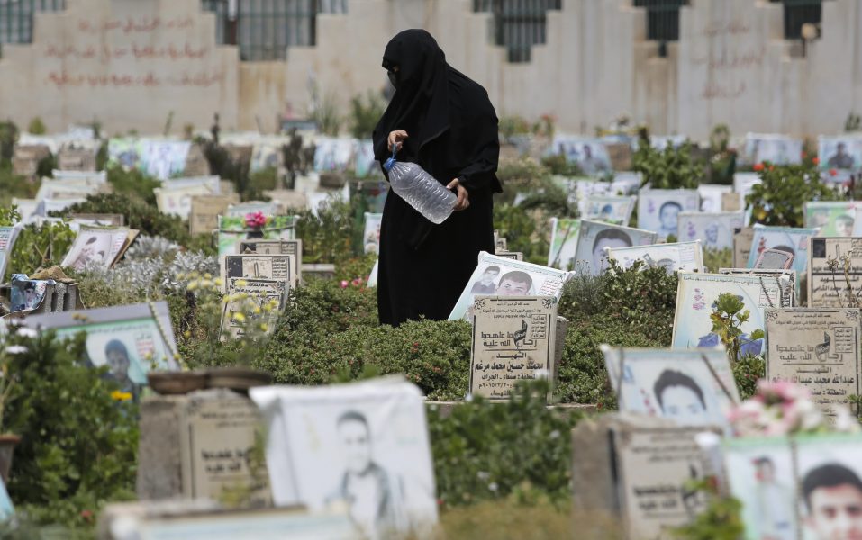 En kvinna  sköter graven till en dödad släkting på kyrkogården i Sanaa i Jemen.