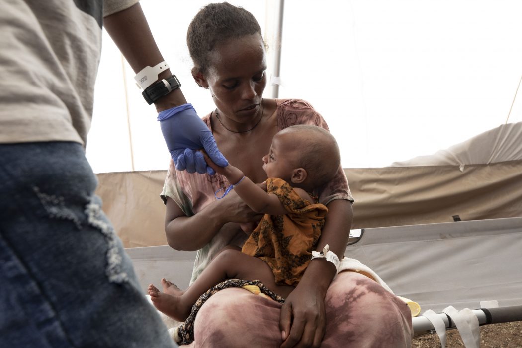 En tigreansk kvinna som flytt hemregionen sitter med sitt barn i ett flyktingläger i Sudan.
