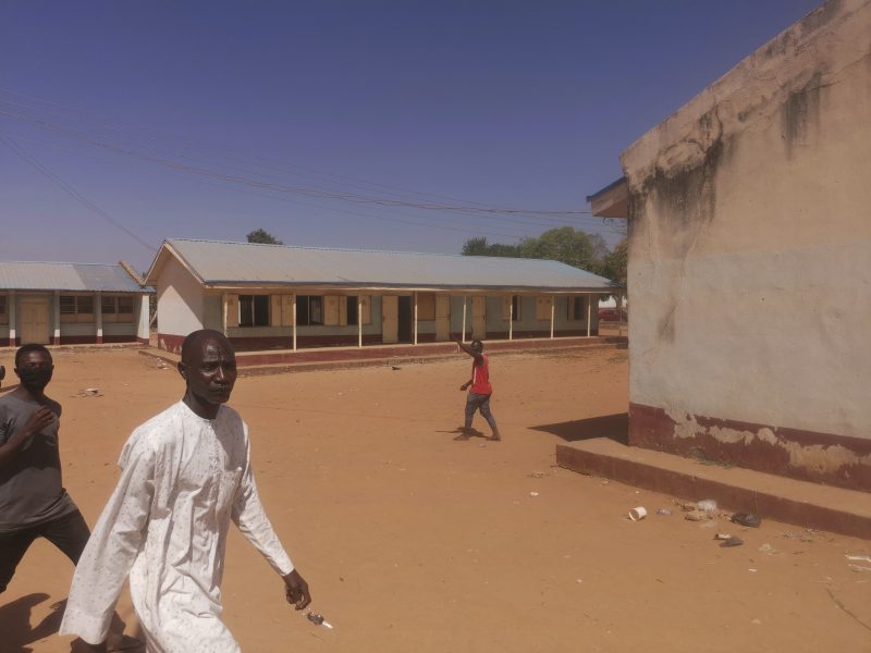 Människor samlas utanför skolan i Kankara i Nigeria där beväpnade män stormade byggnaderna i fredags.