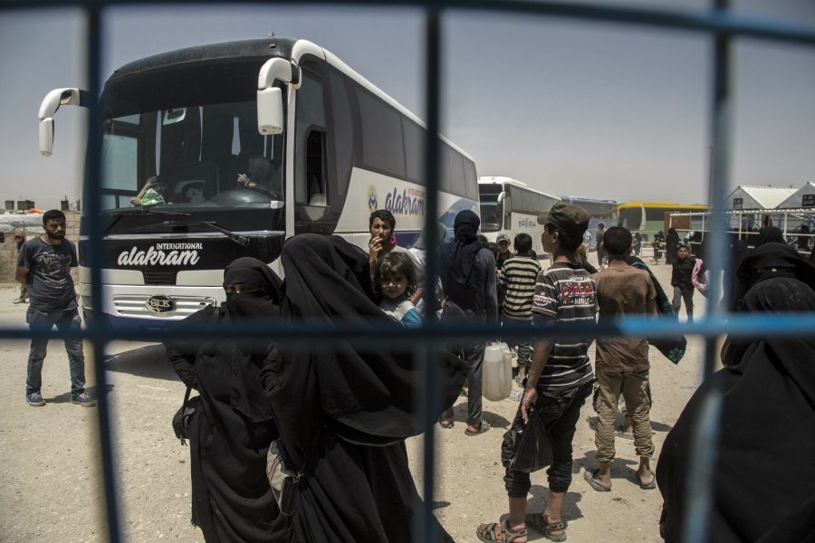 Kvinnor och barn väntar på bussar vid Al-hol-lägret i Syrien.