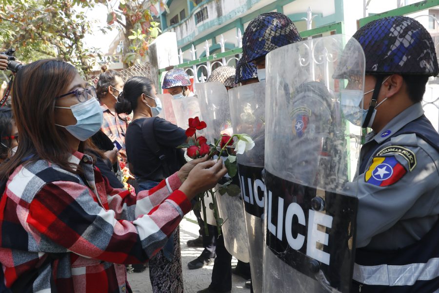 Demonstranter försöker under fredagens demonstrationer i Myanmar ge polisen röda blommor, symbolfärgen för den störtade ledaren Aung San Suu Kyis parti NLD.