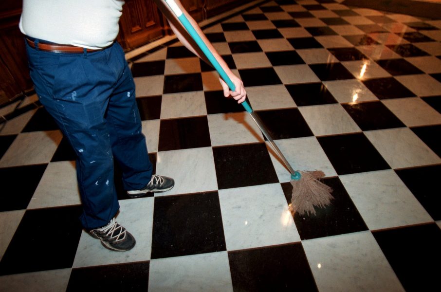  Lokalvårdare/städare moppar vit och svart-rutigt marmor-golv.