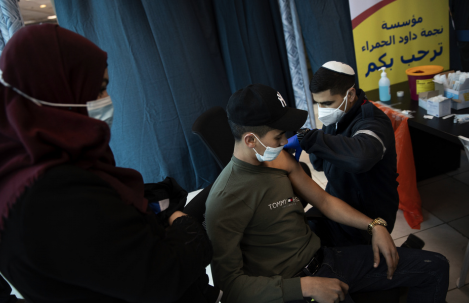 Ett israeliskt vårdlag ger vaccin till palestinier vid kontrollstationen Qalandia mellan Ramallah och Jerusalem.