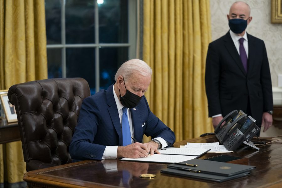 USA:s president Joe Biden skriver under nya presidentdekret medan landets nytillträdde minister för inrikes säkerhet, Alejandro Mayorkas, tittar på.
