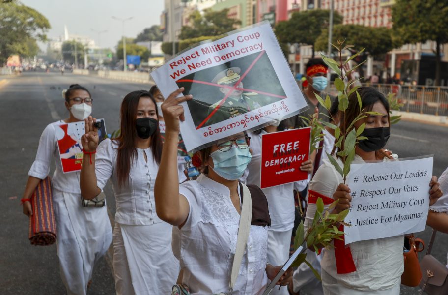 Demonstranter håller upp plakat med överkryssade bilder på juntaledaren Min Aung Hlaing.