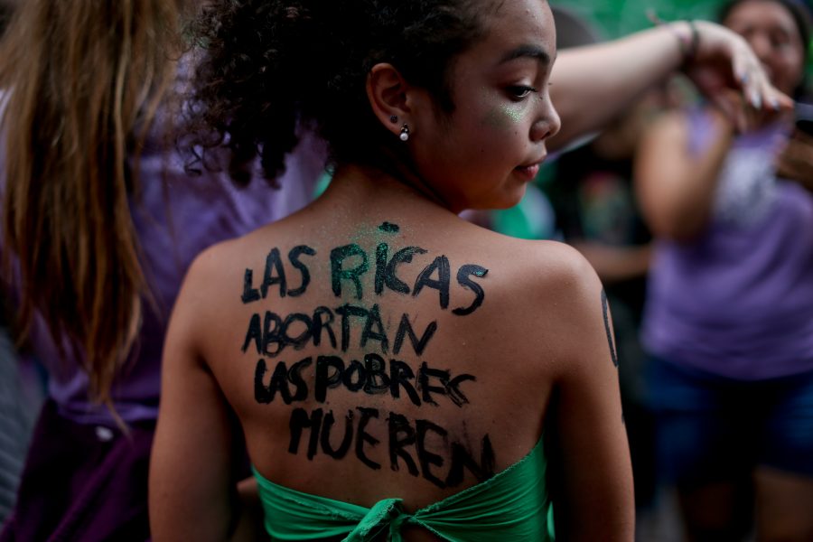En ung aborträttsaktivist med texten "rika gör abort, fattiga dör" på ryggen under en demonstration för legalisering av abort i Buenos Aires, Argentina.