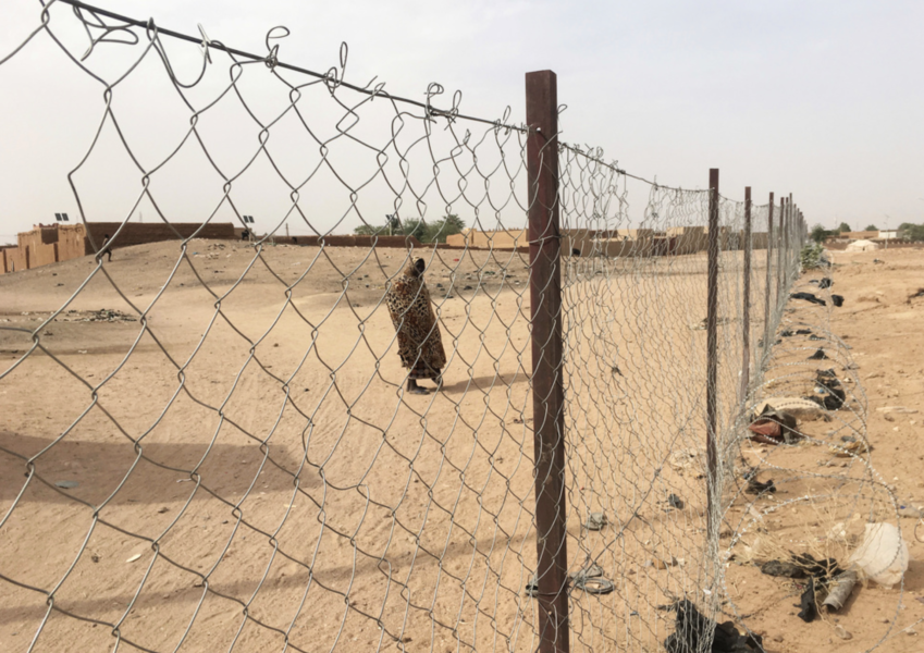 Ett kvínna står utanför ett dammigt flygfält i Niger, som lider av krig.