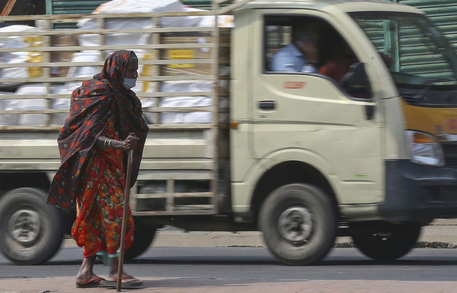 En indisk kvinna med munskydd ber om allmosor/hjälp vid ett trafikljus i Hyderabad i Indien.