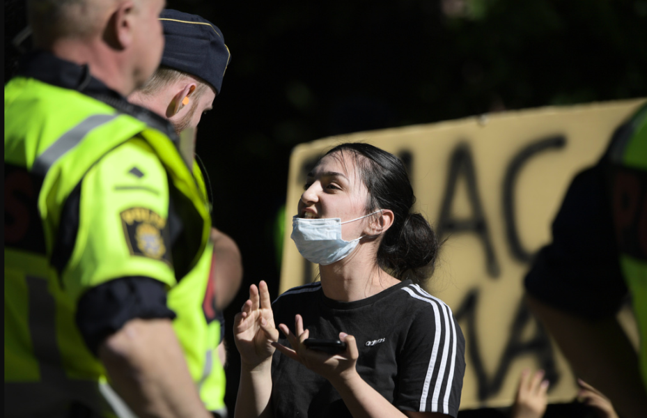 Två poliser diskuterar med en deltagare i en demonstration utan tillstånd under BLM-protester i Stockholm sommaren 2020.