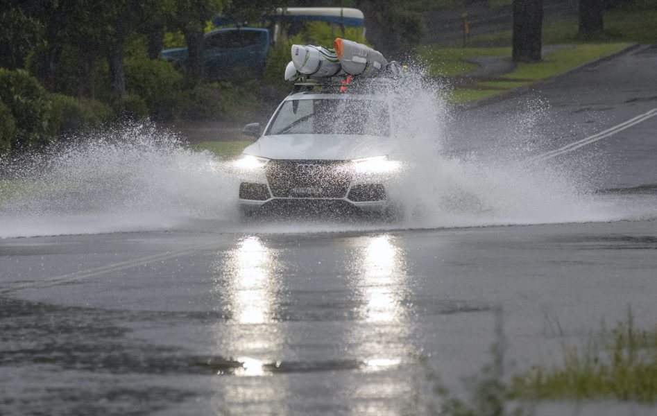 En bil kör i ett översvämmat Port Stephens, 20 mil norr om Sydney.