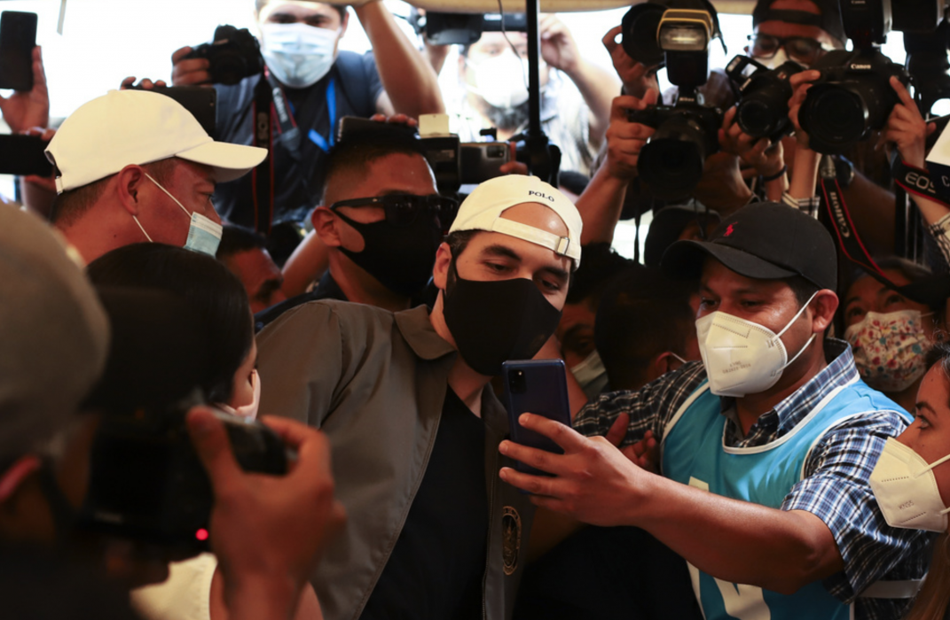 El Salvadors president Nayib Bukele, i vit keps, poserar för en selfie med en anhängare när han lägger sin röst i parlamentsvalet i söndags.