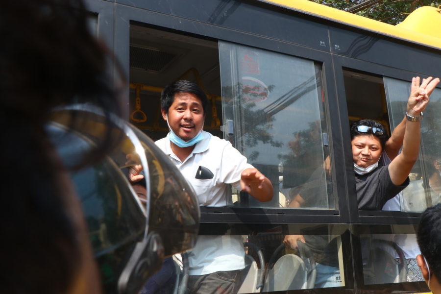 Demonstranter som suttit fängslade i Myanmar vinkar från bussen som fört honom ut från fängelset i Rangoon.