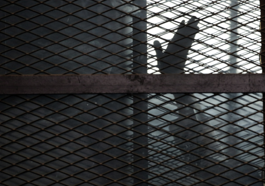 En medlem av Muslimska brödraskapet vinkar från försvarsfållan i en rättegång vid ett fängelse i Kairo.