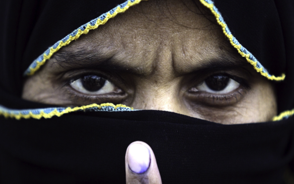 En muslimsk indisk kvinna visar att hon har röstat genom att visa upp sitt bläckfärgade finger.