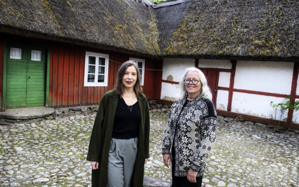 Karin Ohlsson-Leijon (till vänster) och Laila Reppen utanför Skånegården på Skansen i Stockholm, en av alla de hustyper som finns representerade i boken.