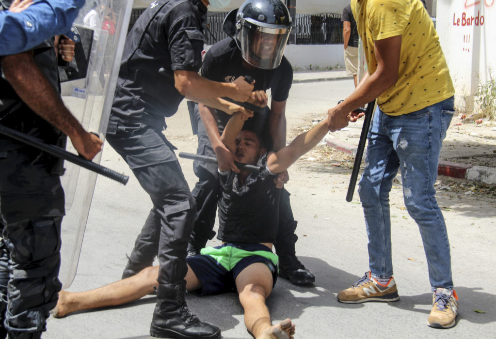 Tunisisk polis griper en demonstrant i huvudstaden Tunis.