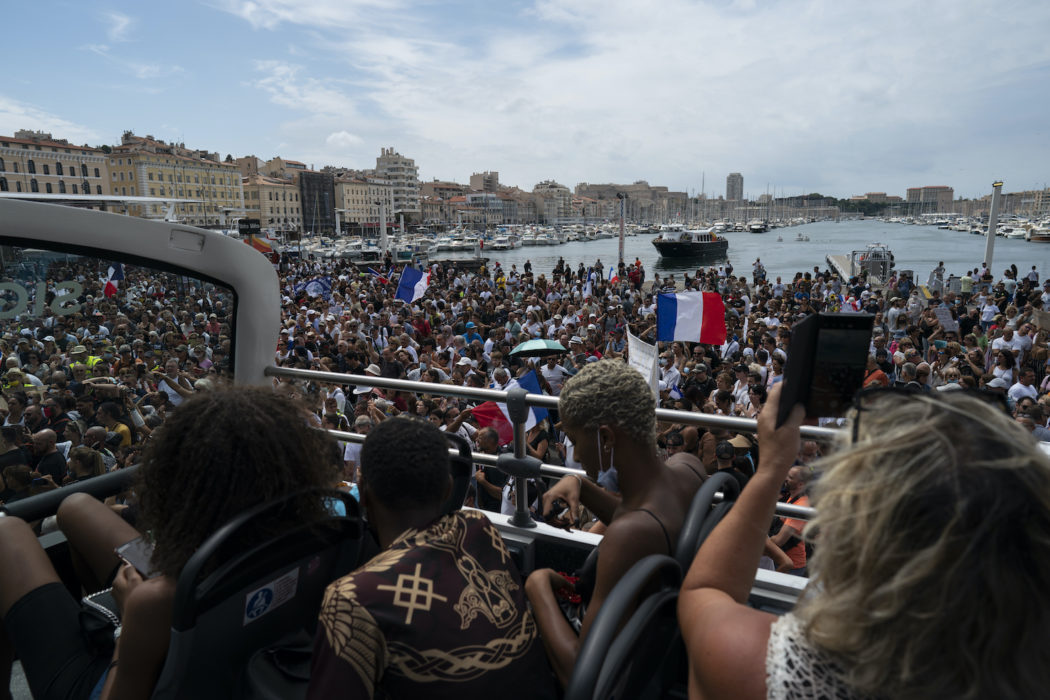 Turister bevittnar protester mot de utvidgade reglerna om covidpass i Marseille i lördags.