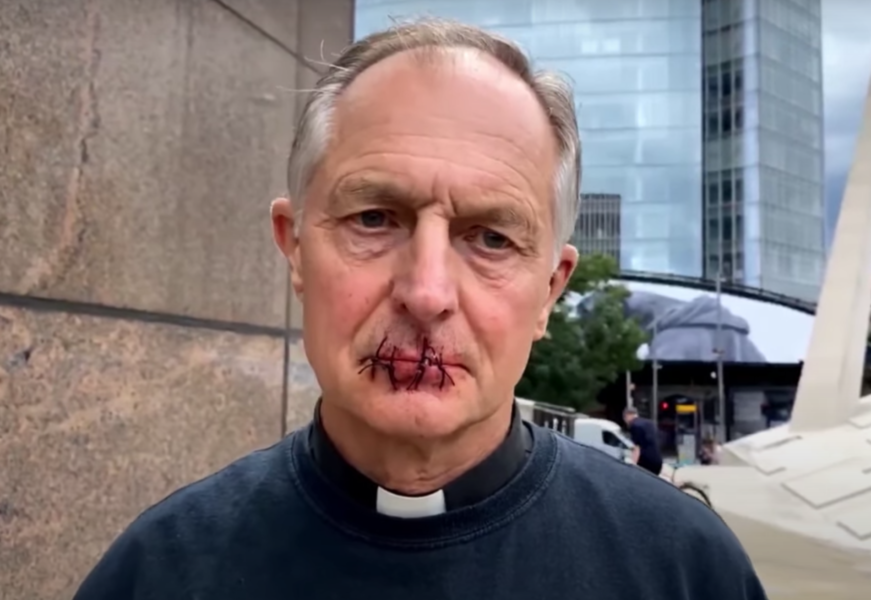 71-årige prästen Tim Hewes protesterade mot Rupert Murdoch, genom att sy ihop sina läppar.