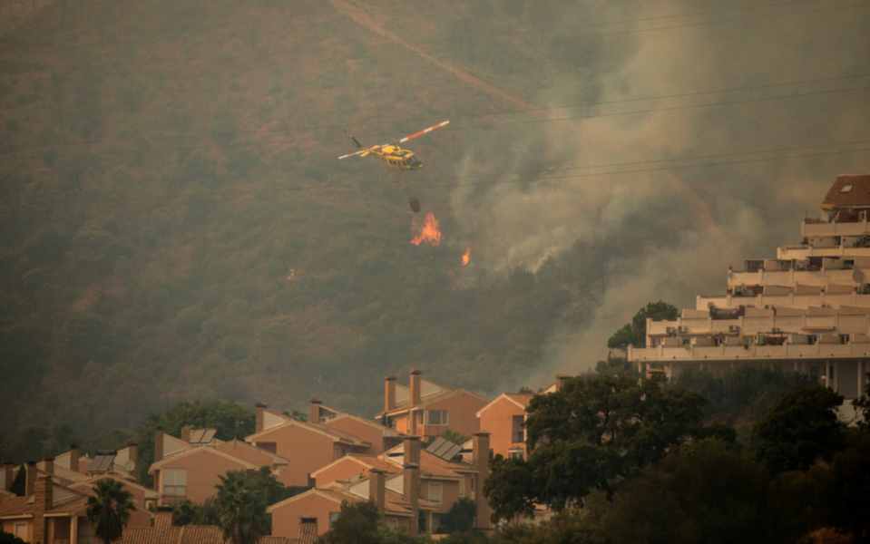 En helikopter vattenbombar branden i Estepona, Spanien.