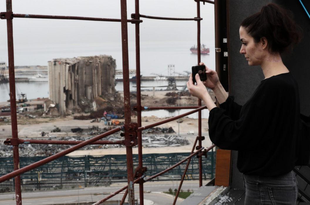 Joana Dagher, 33, som överlevde den våldsamma explosionen i Beirut förra året, tar en bild av hamnen ett halvår efter detonationen.