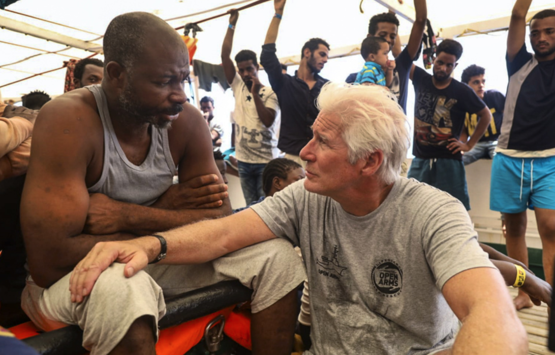 Skådespelaren Richard Gere pratar med en migrant ombord fartyget Open Arms 2019.
