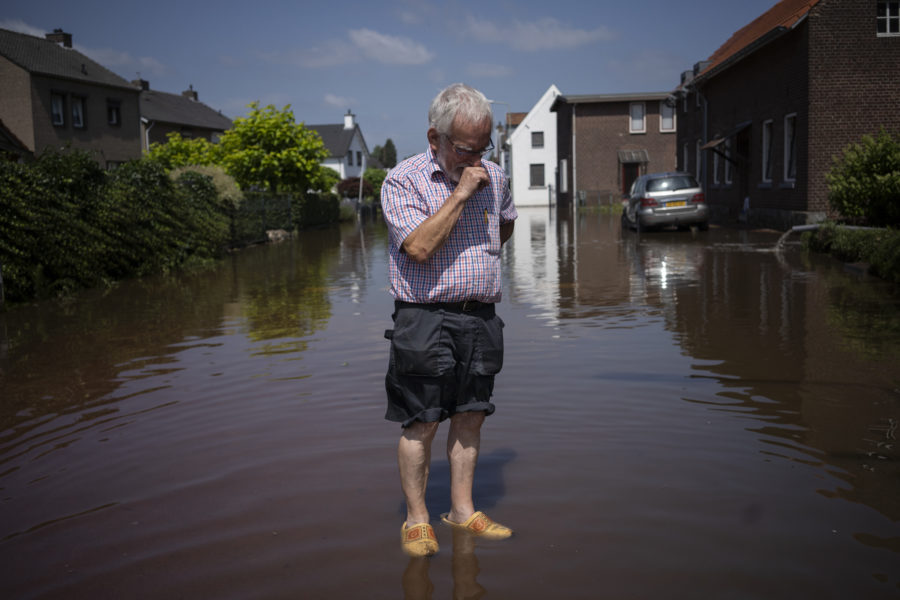 En man står utanför sitt översvämmade hus i nederländska Brommelen.