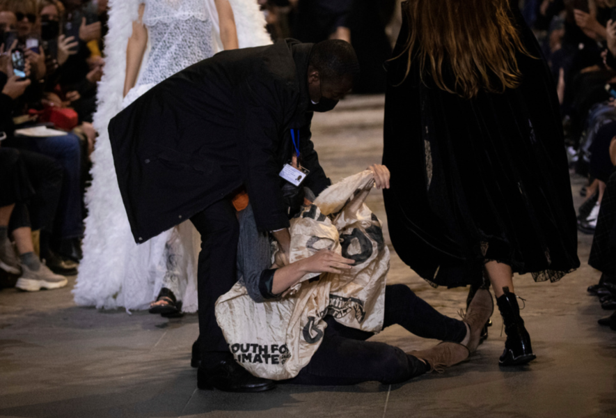 En klimataktivist som tagit sig upp på catwalken i Paris, brottades ner och avlägsnades av vakter.