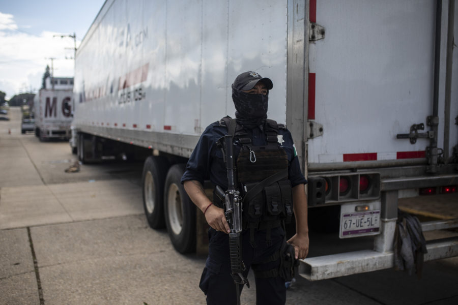 En polis vaktar en av de två lastbilarna i vilka runt 600 migranter försökte ta sig till USA.