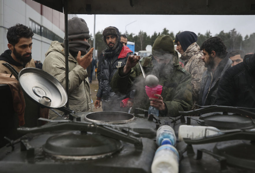 Migranter får mat av belarusiska soldater vid gränsen mellan Belarus och Polen.