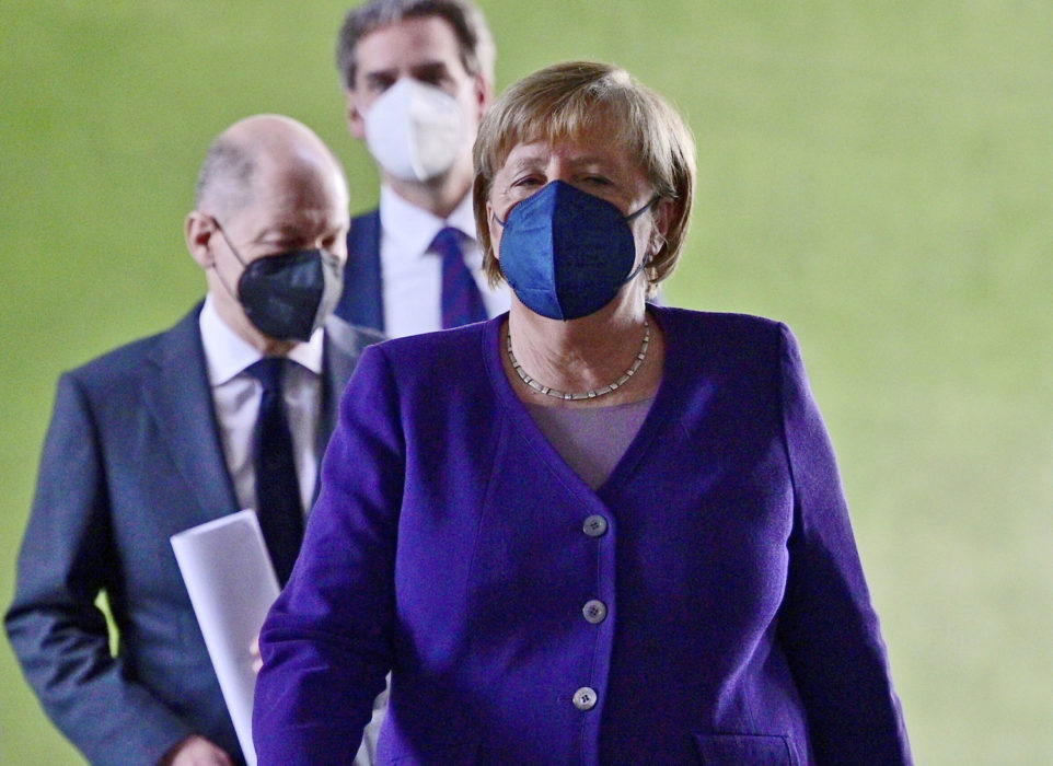 Tysklands avgående förbundskansler Angela Merkel, med tillträdande förbundskansler Olaf Scholz strax bakom, har i samråd med förbundsländernas ledare beslutat att skärpa kraven om vaccinering.