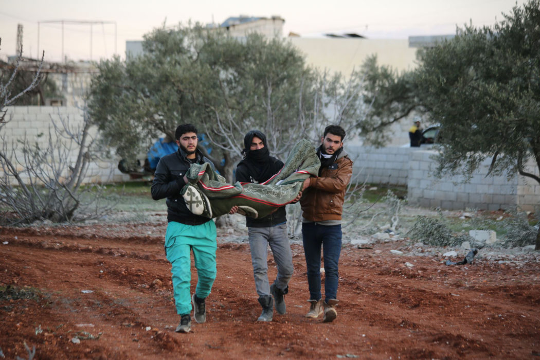 Syriska män bär på ett barns kropp efter ett luftangrepp i februari 2020.