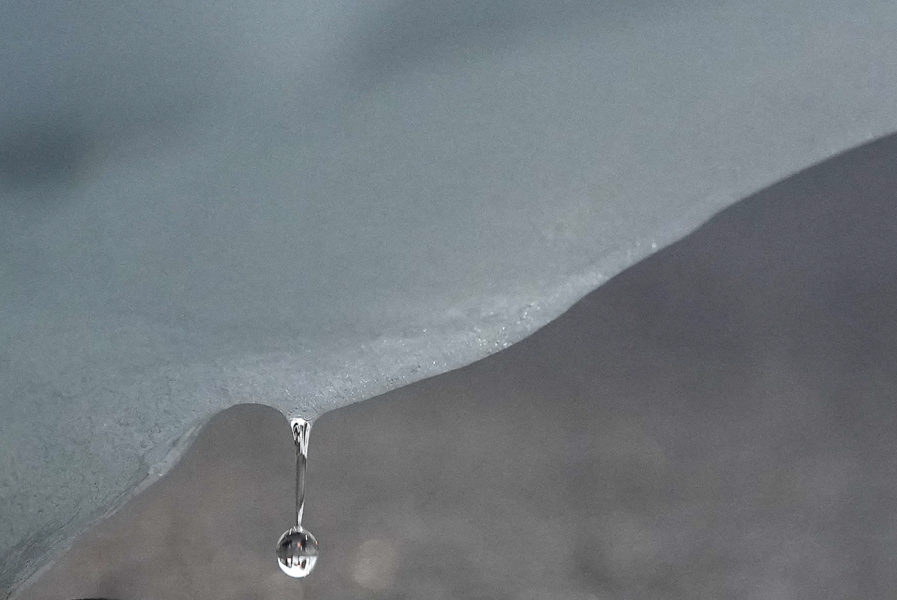 En droppe faller från ett isberg i Arktis.
