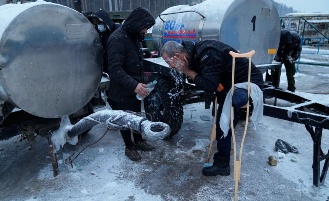 En migrant i Belarus tvättar ansiktet vid ett logistikcenter nära gränsen mot Polen.