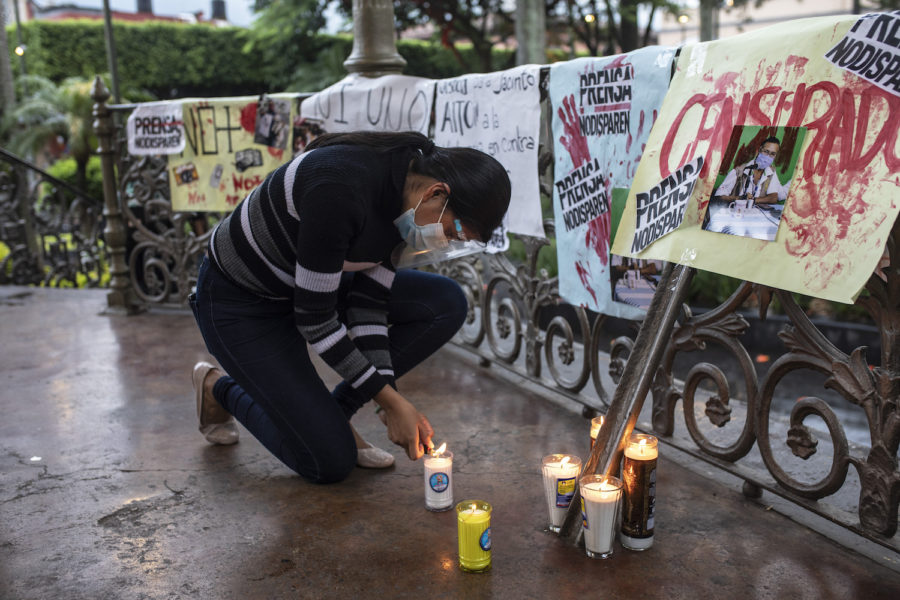 En kvinna tänder ett ljus vid en minnesstund för en journalist som mördades i Mexiko i augusti.