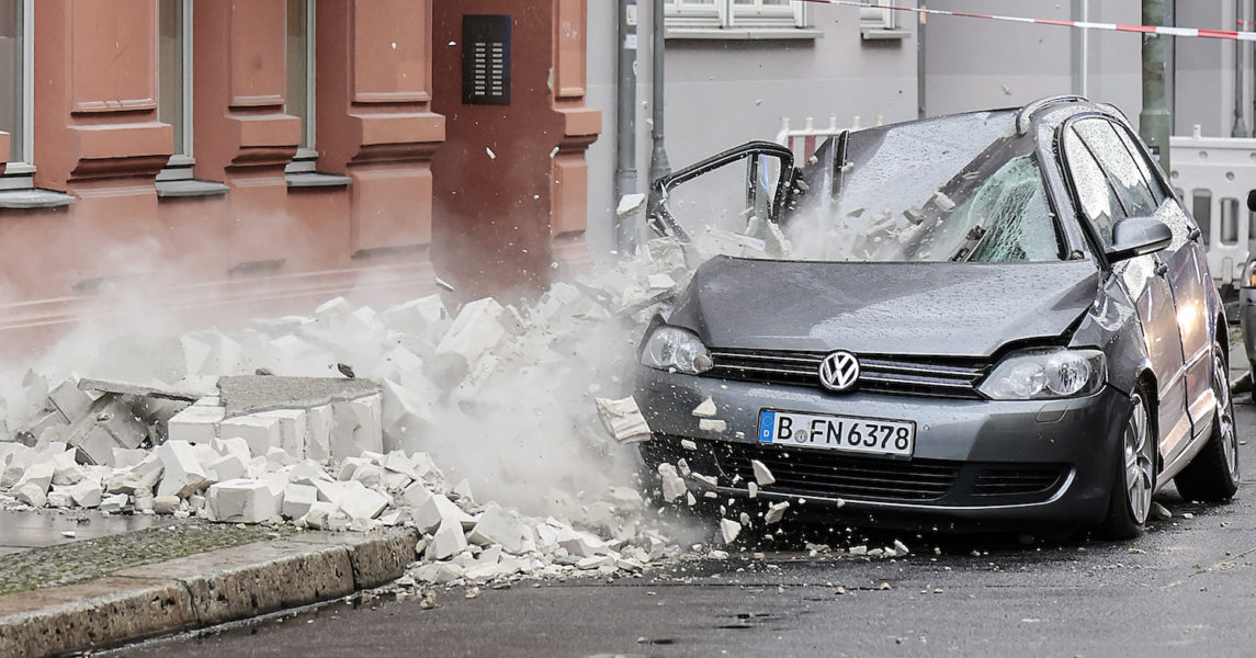 En del av en skadad vägg faller över en parkerad bil i Berlin på torsdagen.