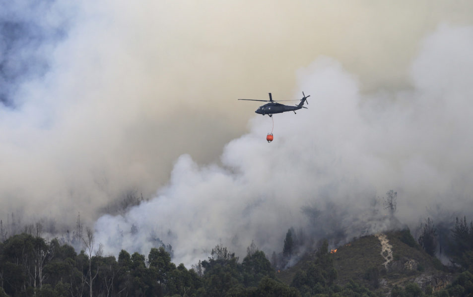 En helikopter vattenbombar en skogsbrand i Colombia.
