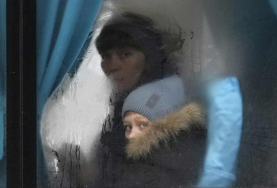 En kvinna och hennes barn på en buss i färd att lämna Luhansk i östra Ukraina, efter Rysslands attack på torsdagen.