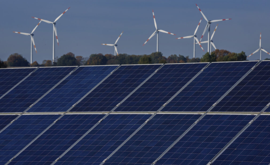 Solceller med vindkraftverk i bakgrunden i Rapshagen i Tyskland.