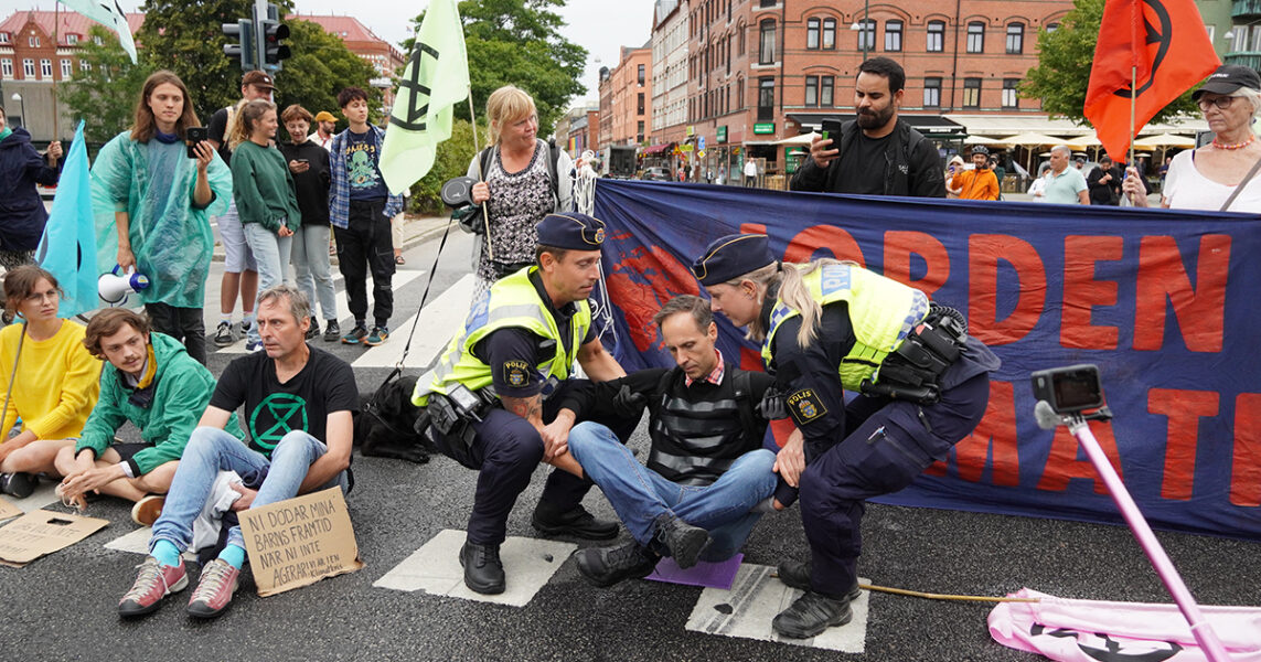 Polisen bär bort Martin Smedjeback från en gata i Malmö, där han genomför en manifestation tillsammans med andra i Extinction rebellion den 14 augusti 2021.