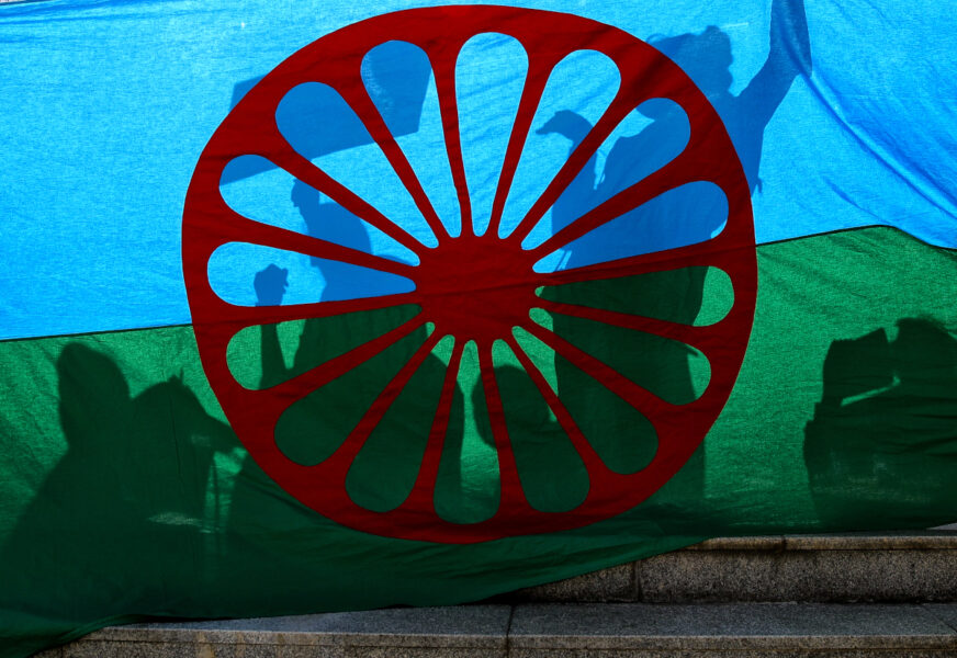 Det röda hjulet i den romska flaggan symboliserar vandringen från Indien samt romernas  framåtskridande.