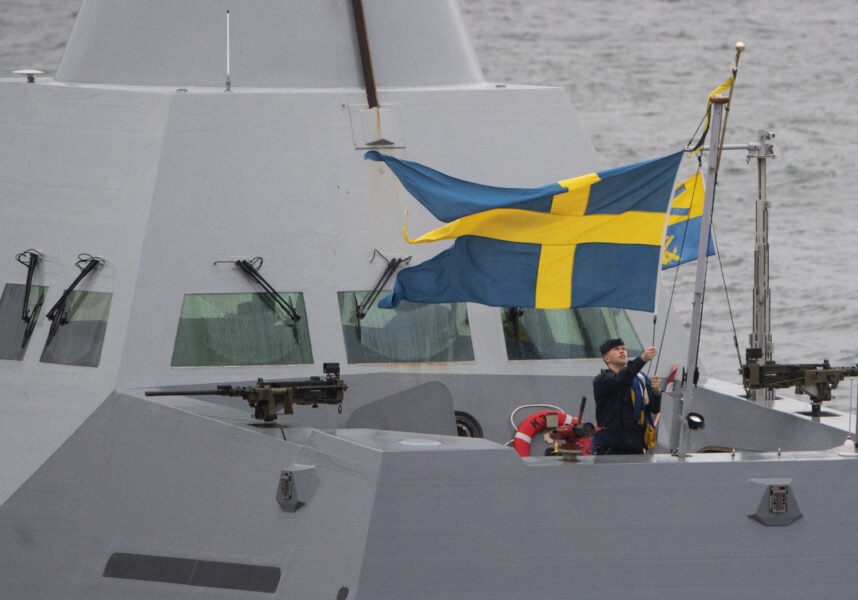 En matros på flottans korvett Helsingborg hissar den svenska flaggan.
