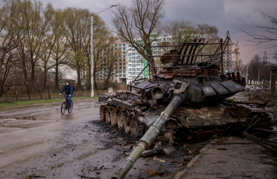 En man cyklar förbi en förstörd rysk stridsvagn i Tjernihiv.