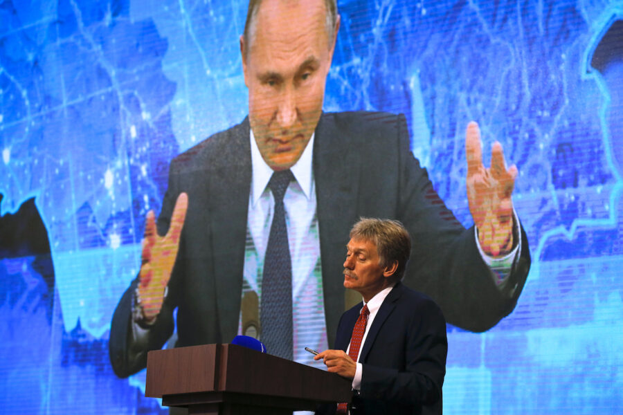 Kremls talesperson Dmitrij Peskov tittar på medan president Vladimir Putin talar via länk under en pressträff.