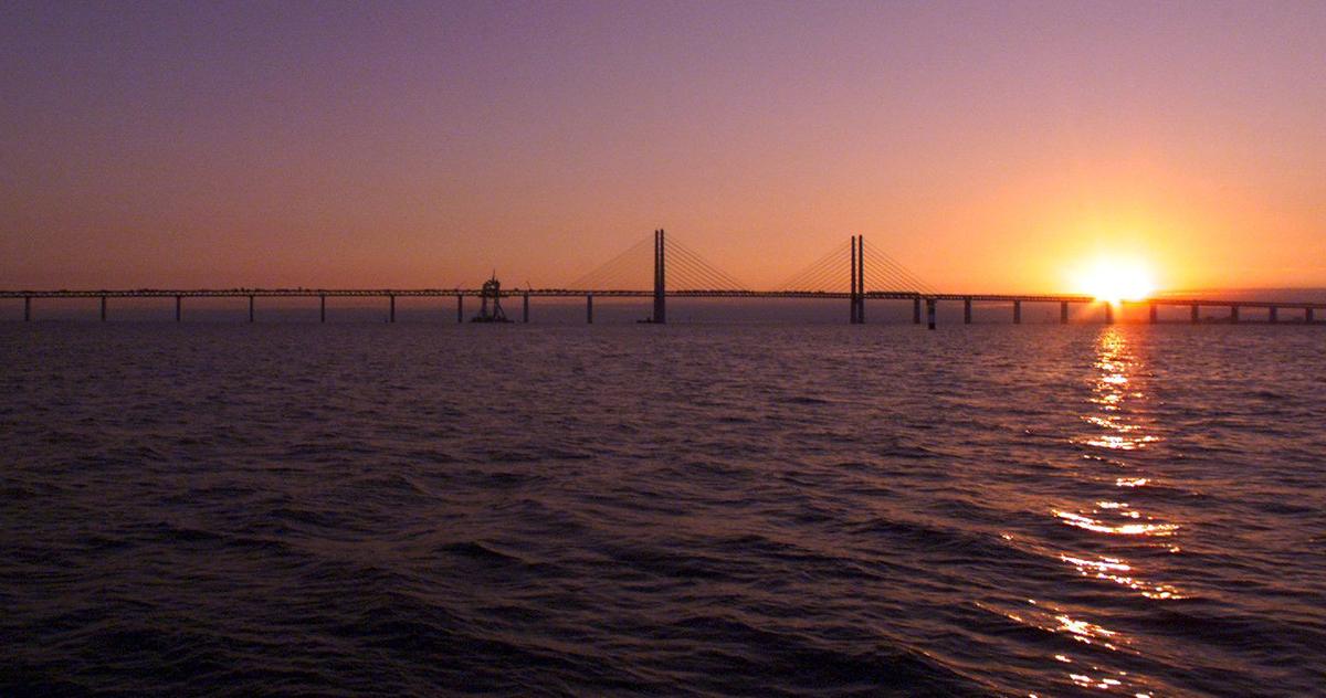Jorden värms av solen som här går upp över Öresundsbron.