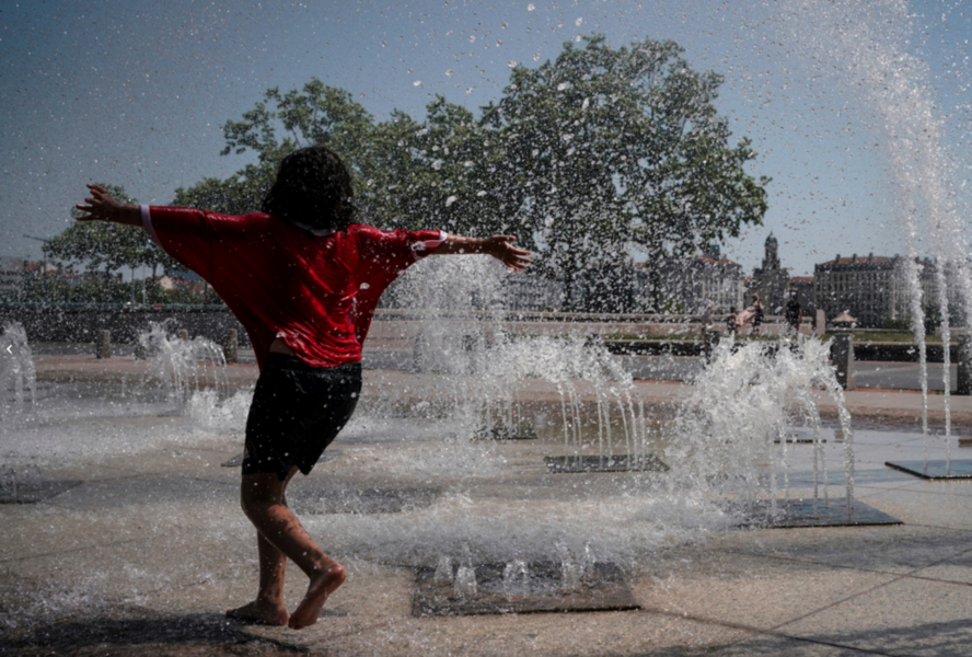 Ett barn leker i en fontän i Lyon i Frankrike den 19 juni – som då plågades av en ovanligt tidig värmebölja.